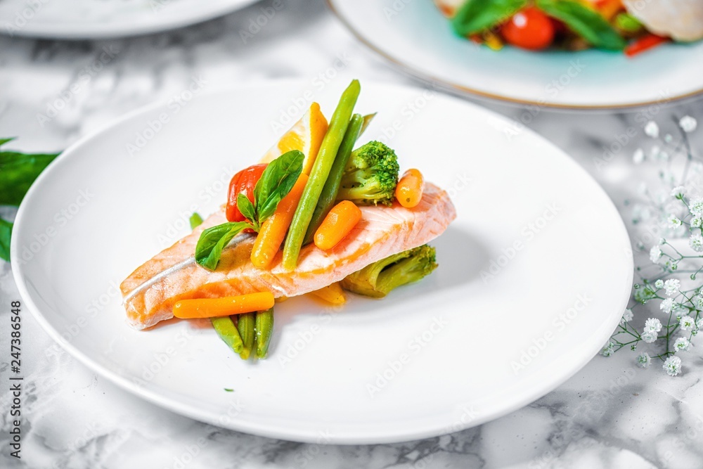 steamed salmon steak with vegetables on a white marble table steamed salmon steak with vegetables on a white marble table