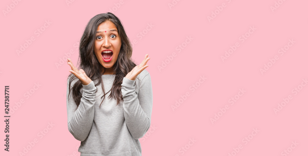 Portrait of young indian woman surprised and shocked, looking with wide eyes, excited by an offer or by a new job, win concept