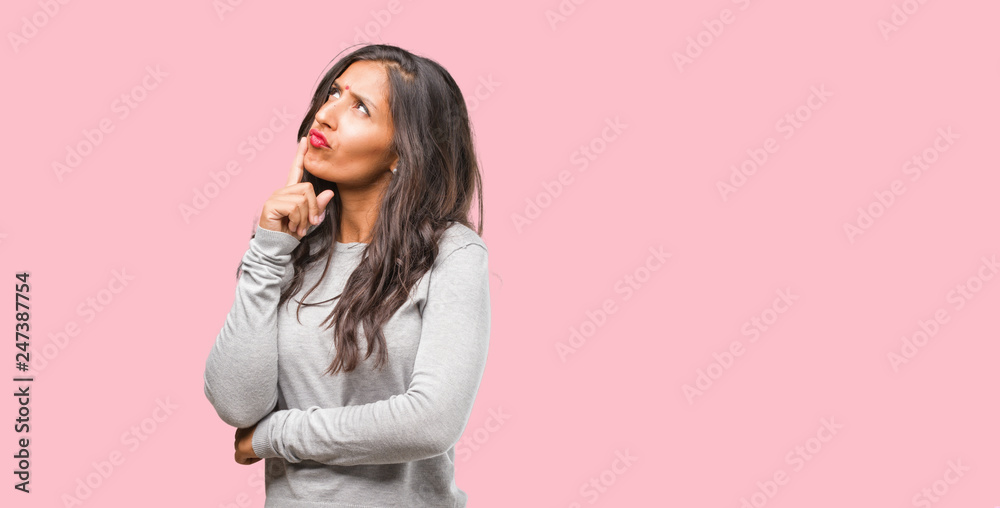 Portrait of young indian woman thinking and looking up, confused about an idea, would be trying to find a solution Portrait of young indian woman thinking and looking up, confused about an idea, would be trying to find a solution