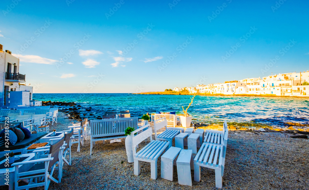 white restaurant tables on turquoise stony bay of greek island Paros