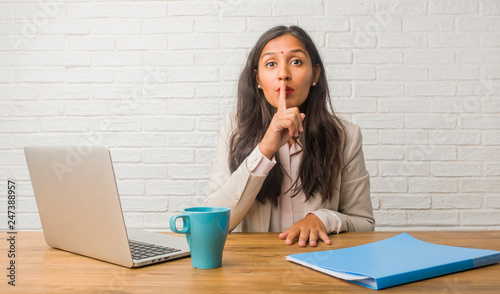 Young indian woman at the office keeping a secret or asking for silence, serious face, obedience concept