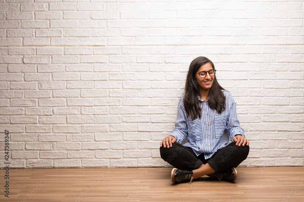 Young indian woman sit against a brick wall laughing and having fun, being relaxed and cheerful, feels confident and successful Young indian woman sit against a brick wall laughing and having fun, being relaxed and cheerful, feels confident and successful
