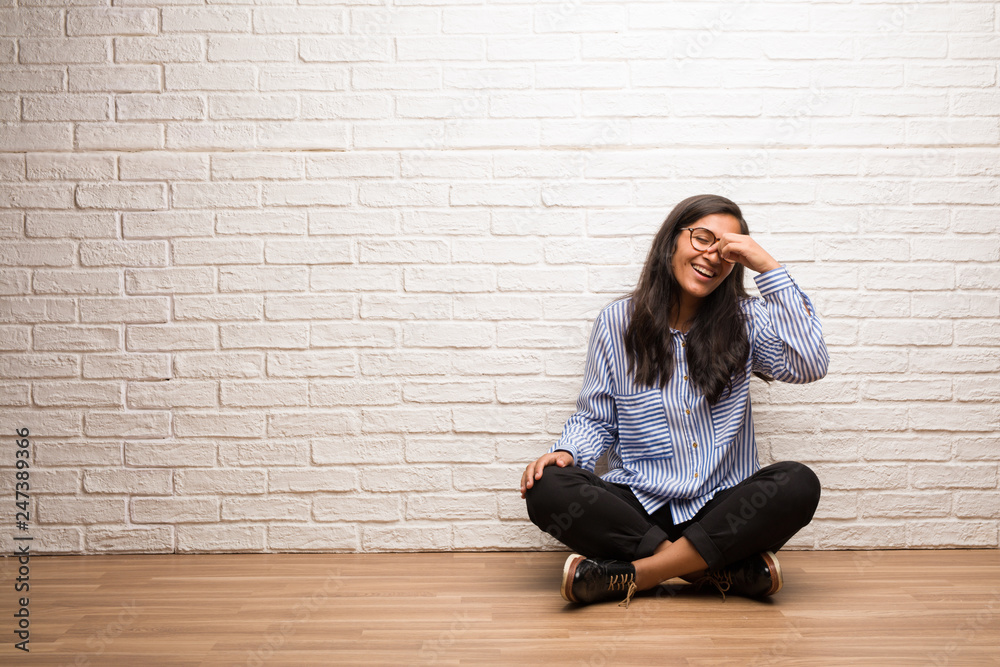 Young indian woman sit against a brick wall laughing and having fun, being relaxed and cheerful, feels confident and successful Young indian woman sit against a brick wall laughing and having fun, being relaxed and cheerful, feels confident and successful