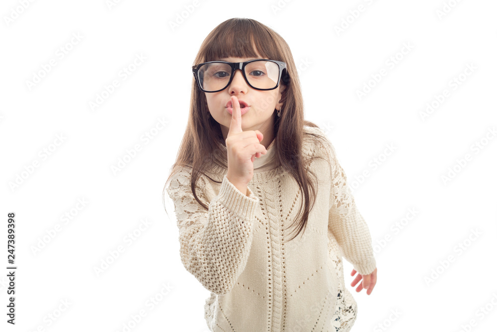 Shh! Secret, little girl in glasses holds finger near lips showing silence sign, isolated on white background. Shh! Secret, little girl in glasses holds finger near lips showing silence sign, isolated on white background.