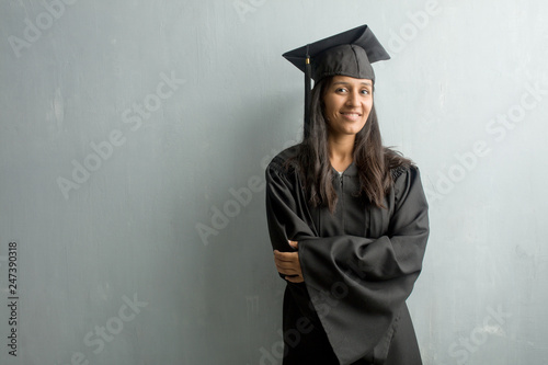 Young graduated indian woman against a wall crossing his arms, smiling and happy, being confident and friendly