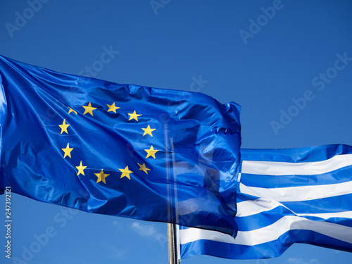 Greek and European Union flags waving in blue sky