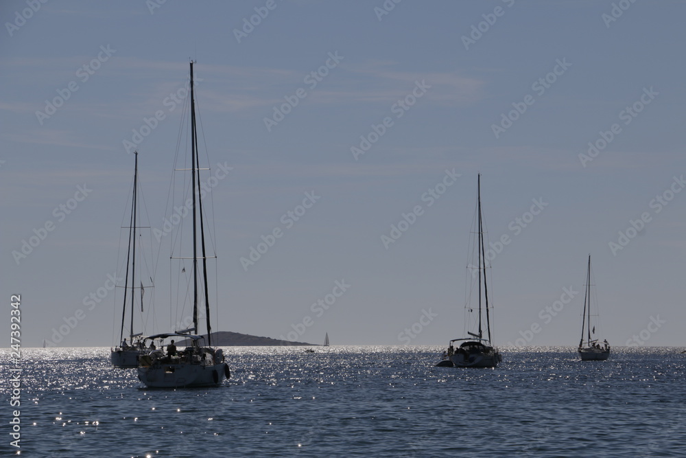 Sailboats, yachts on the Adriatic Sea. Beautiful weather. Sunny, hot, summer day on the Croatian coast. Primosten, Croatia. Rocky shore, mediterranean vegetation, riviera, seashore