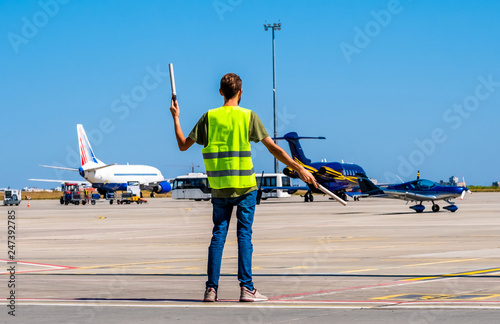 Dispatcher geaturing signs directing the blue shiny sport plane on the airport runway