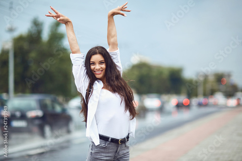 Happy brunette girl holding her hands up on a city street