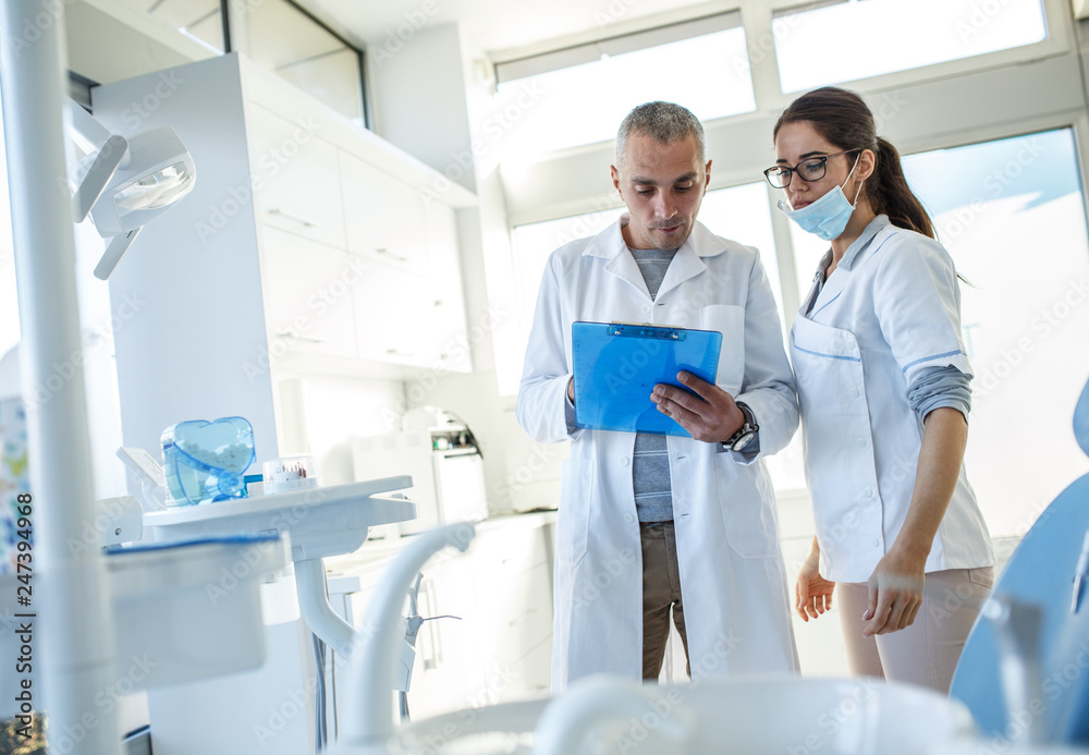 Medical dentist team in dental office examining list of patients. Medical dentist team in dental office examining list of patients.