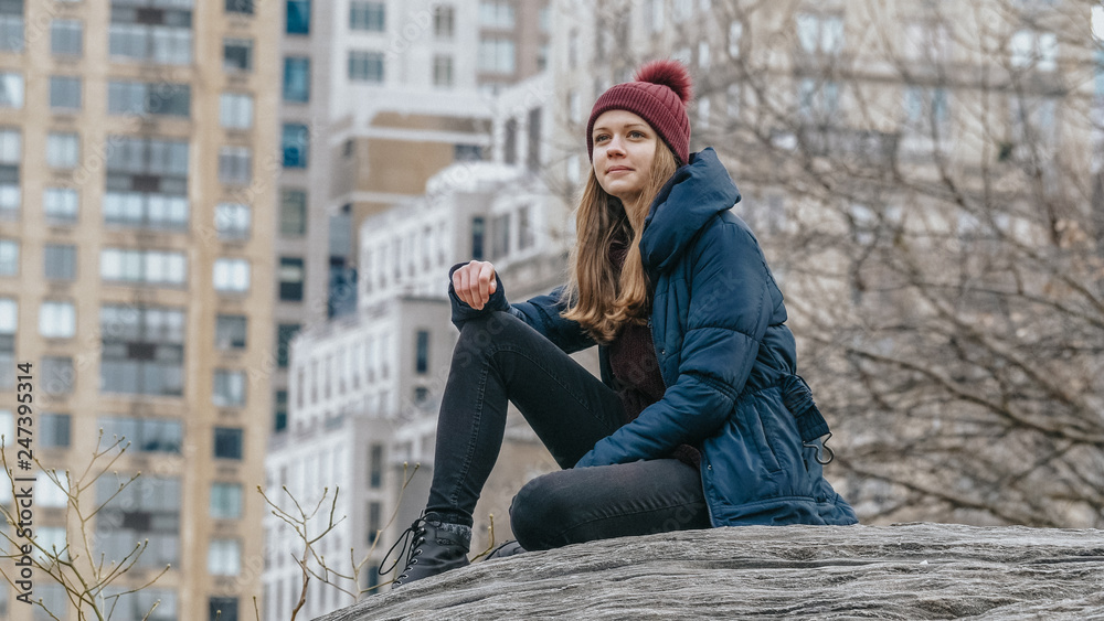 Young woman relaxes on a rock at Central Park New York