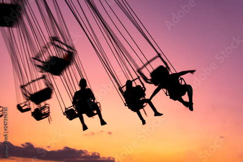 silhouette of people having fun in mechanical game, flying chairs in Guatemala, Retalhulehu. Tropical afternoon.