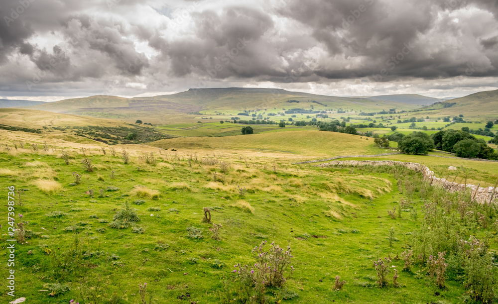 a valley of farm land and hills in England. Handmade stone walls and fields. 