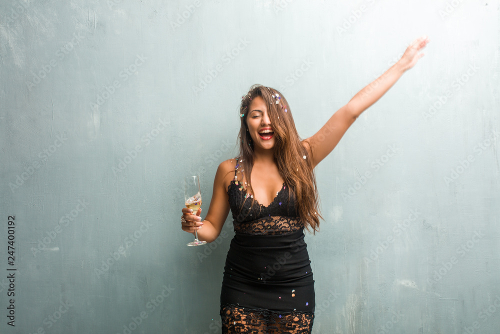 Young latin woman celebrating new year or an event. Excited and happy, holding a champagne bottle and a cup. Young latin woman celebrating new year or an event. Excited and happy, holding a champagne bottle and a cup.