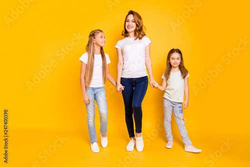 Full length body size view portrait of three nice cute winsome attractive slim cheerful people holding hands mum mommy isolated over bright vivid shine yellow background