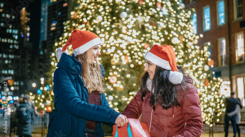 Two girls in front of a Christmas tree enjoy the wonderful time in New York