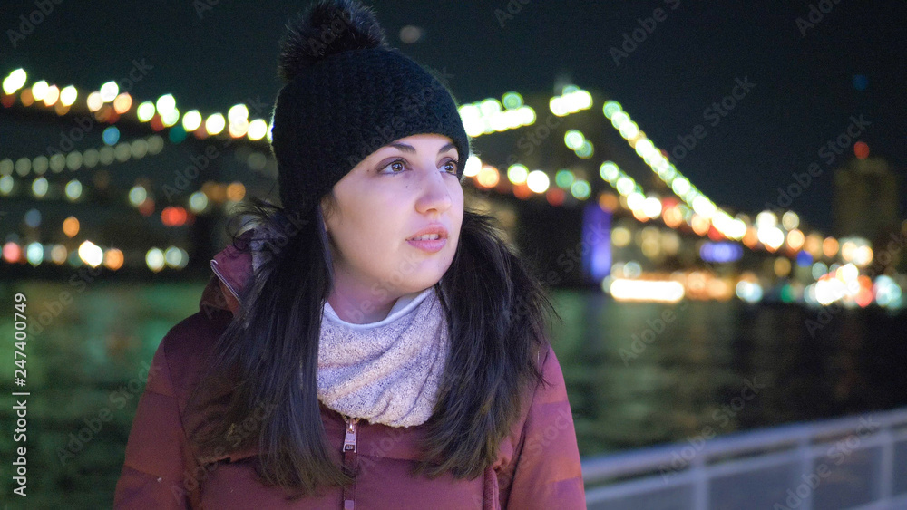 Young woman sits at Brooklyn Bridge New York by night Young woman sits at Brooklyn Bridge New York by night