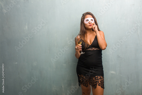 Portrait of young pretty woman wearing a dress against a wall thinking and looking up, confused about an idea, would be trying to find a solution