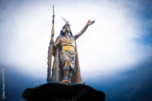 Bottom view of shiny golden statue of Pachacuti on the pedestal on the sky background in Cusco photo