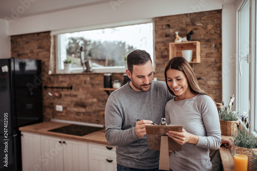 Cute millenial couple making a list not to forget anything.