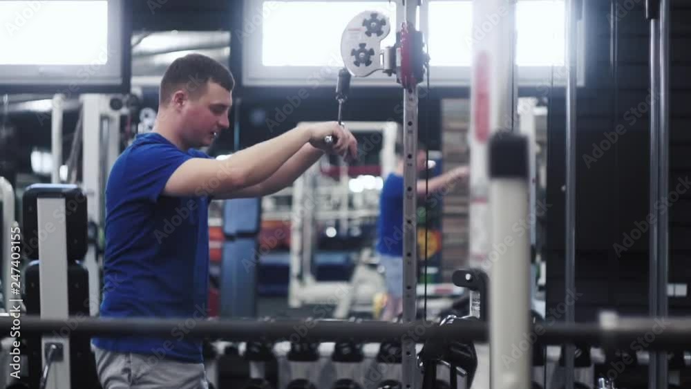 Handsome attractive man cable rope triceps push down exercise while working out in gym