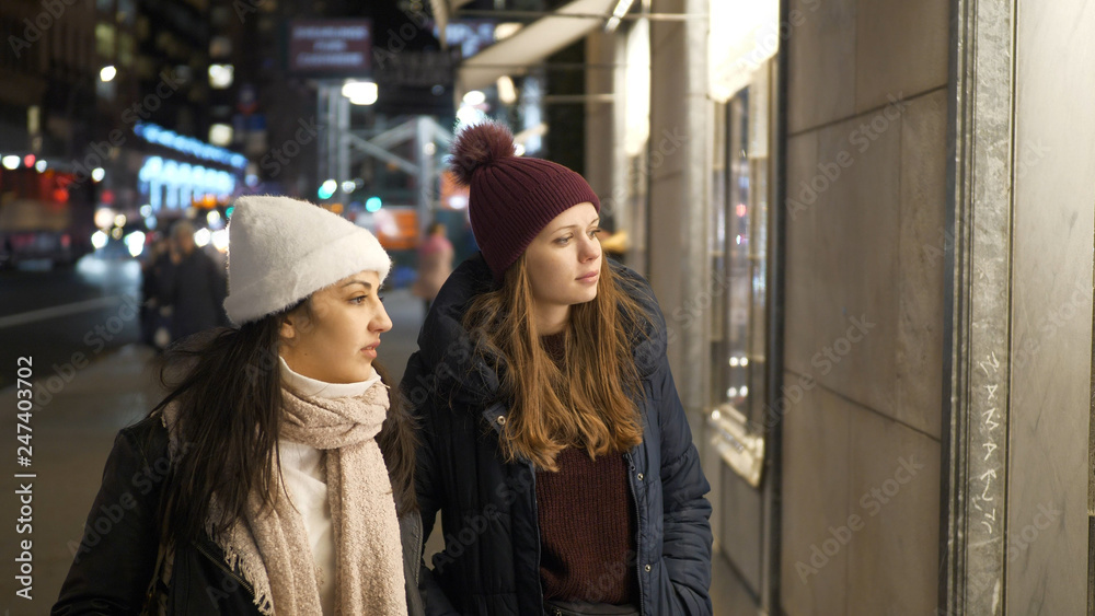 Naklejka premium Two girls on a shopping trip in New York walk along shop windows