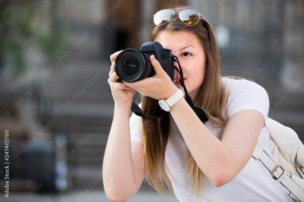 Cheerful girl is taking photos on her camera