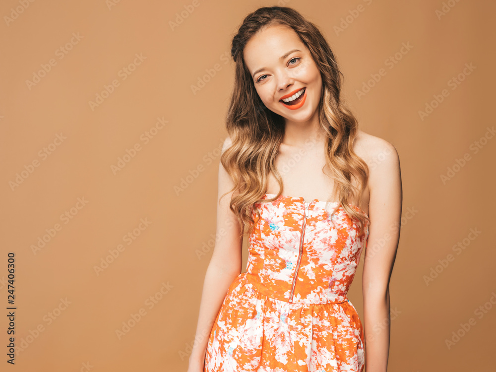 Portrait of beautiful smiling cute model with pink lips. Girl in summer hipster colorful dress. Model posing on golden background