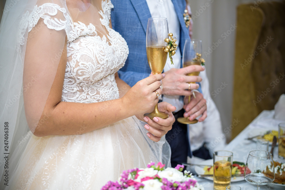Bride and groom at the wedding table. holding a glass of champagne Bride and groom at the wedding table. holding a glass of champagne