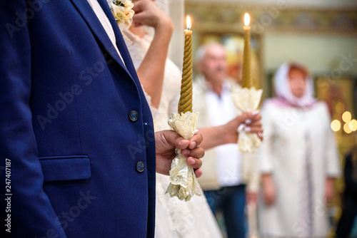 Bride and groom stand with crowns during the ceremony in church