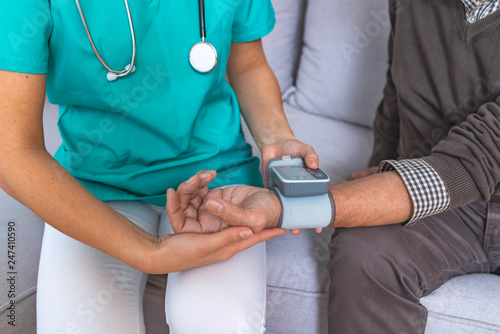 Canvas Print Nurse doing blood pressure monitoring for senior man at home
