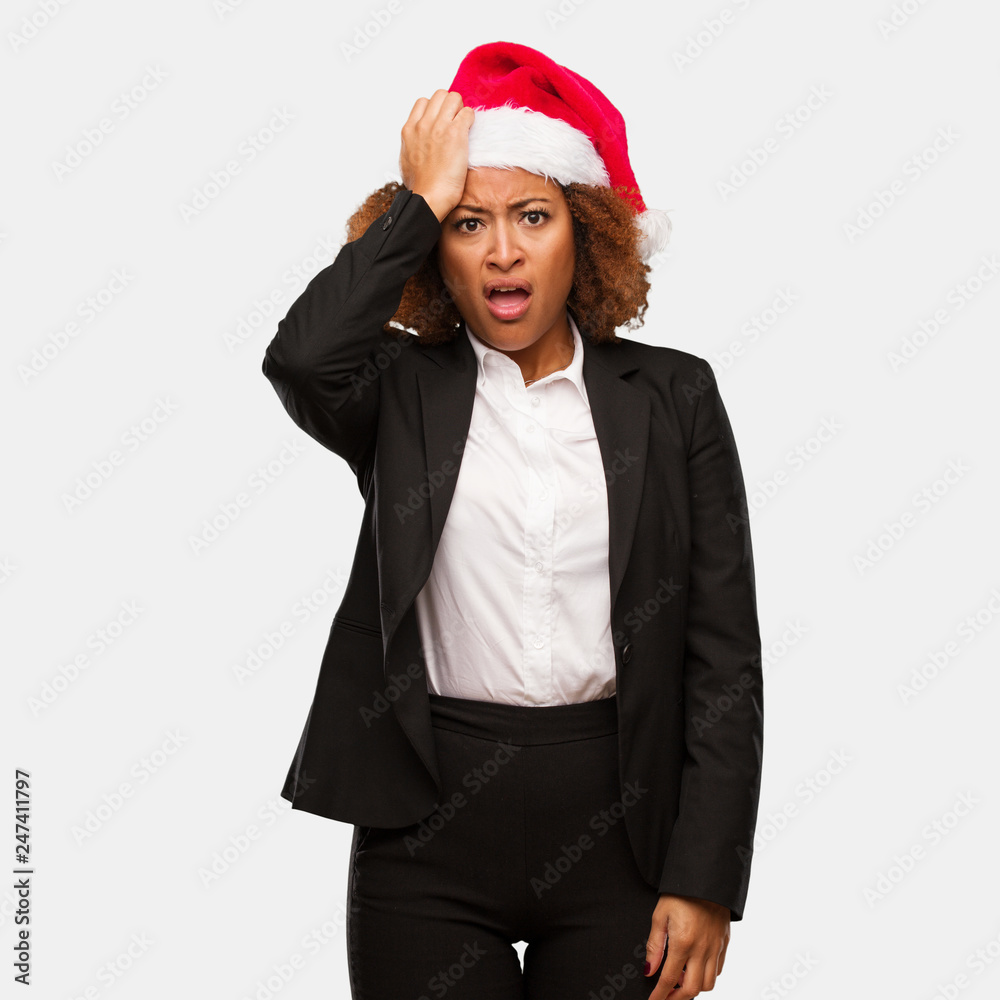 Young business black woman wearing a chirstmas santa hat tired and very sleepy Young business black woman wearing a chirstmas santa hat tired and very sleepy