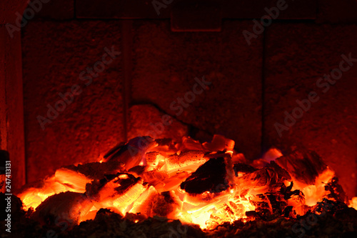 Background of burning hot coals.Coals in the brazie.Embers and fire above firebrand in hearth, shallow DOF. Embers in the fireplace photo