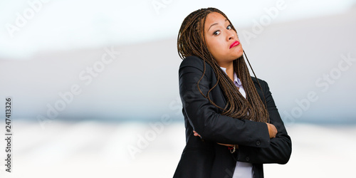 Portrait of a young black business woman doubting and shrugging shoulders, concept of indecision and insecurity, uncertain about something