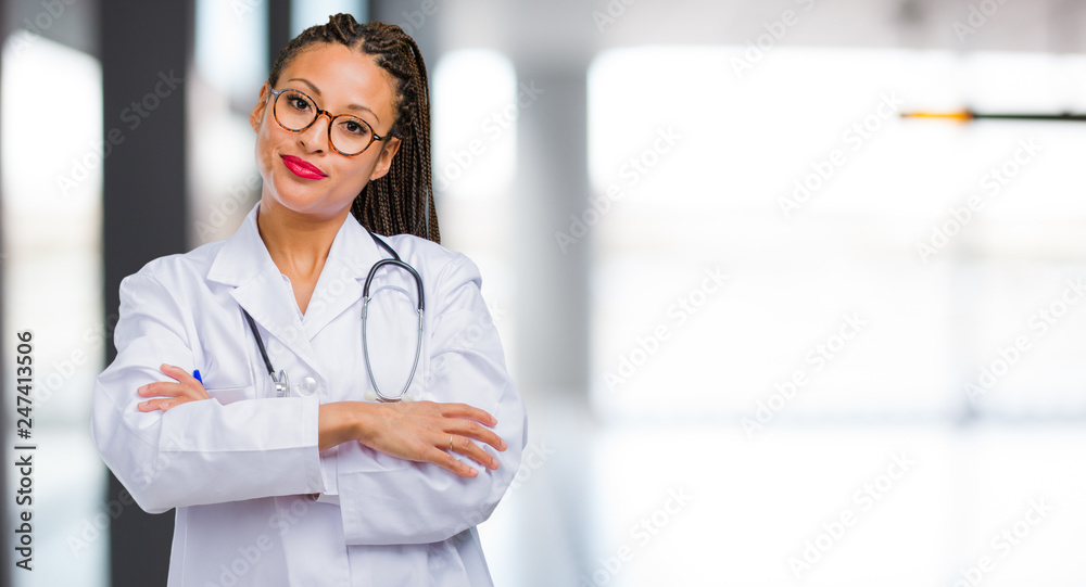 Portrait of a young black doctor woman crossing his arms, smiling and happy, being confident and friendly Portrait of a young black doctor woman crossing his arms, smiling and happy, being confident and friendly
