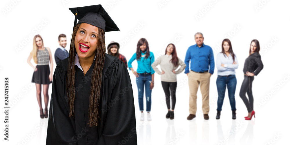 Young graduated black woman wearing braids looking up, thinking of something fun and having an idea, concept of imagination, happy and excited