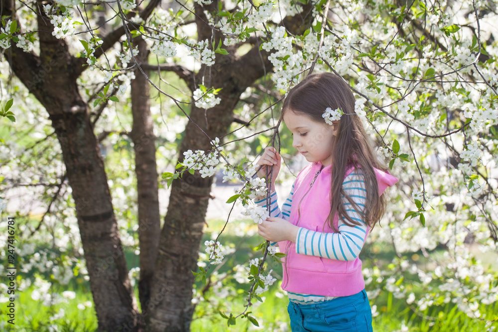 Cute girl in a blooming cherry tree garden