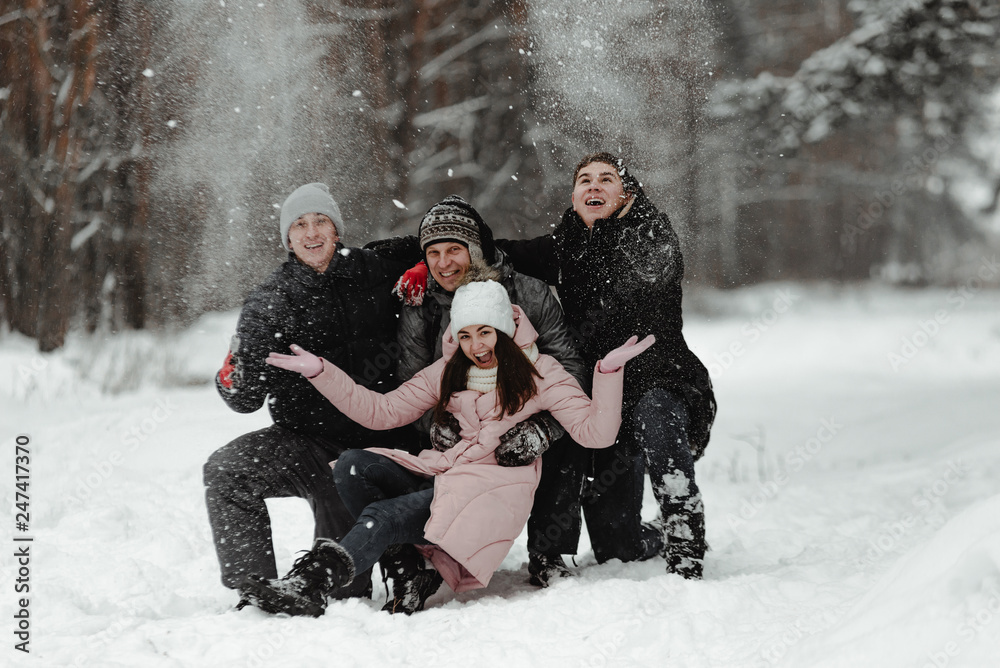 Happy friends in winterwear playing with snow in park. Ukraine 2019