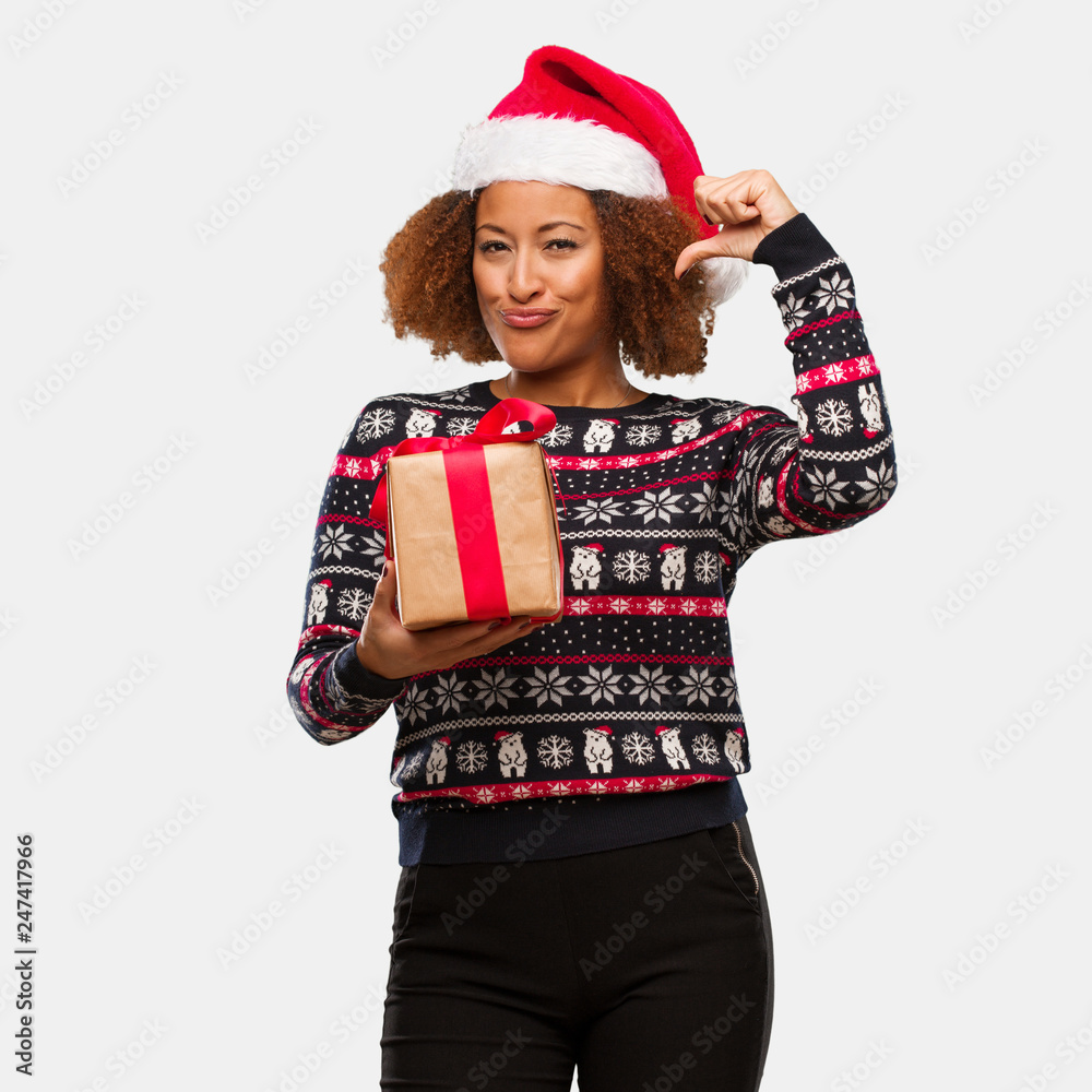 Young black woman holding a gift in christmas day pointing fingers, example to follow Young black woman holding a gift in christmas day pointing fingers, example to follow