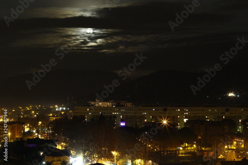 Moon rising behind the clouds in urban landscape, Terni, Umbria, Italia