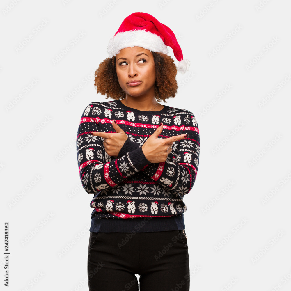 Young black woman in a trendy christmas sweater with print decide between two options Young black woman in a trendy christmas sweater with print decide between two options