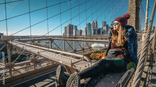 Young beautiful woman on Brooklyn Bridge New York enjoys a wonderful sunny day © 4kclips