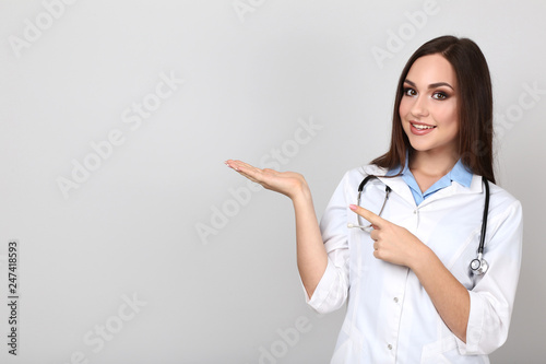 Portrait of young doctor with stethoscope on grey background