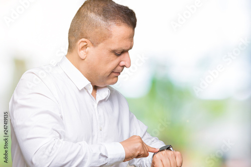 Middle age arab elegant man over isolated background Checking the time on wrist watch, relaxed and confident