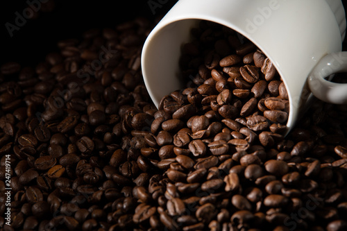 white cups with a pattern and grains of coffee on a black background