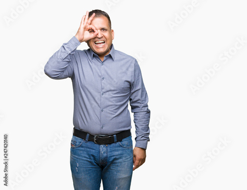 Middle age arab business man over isolated background doing ok gesture with hand smiling, eye looking through fingers with happy face.