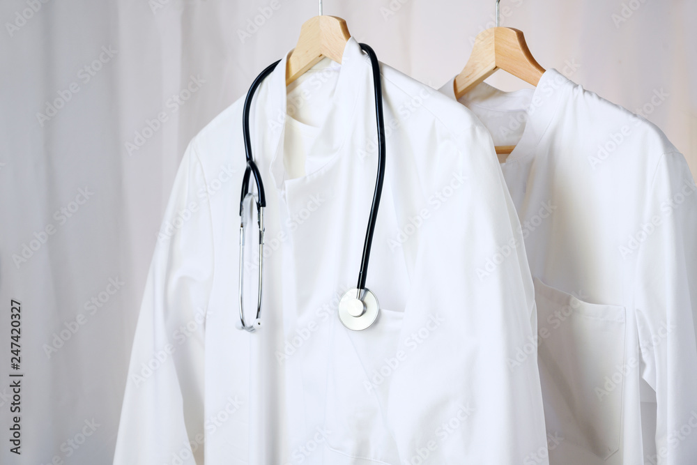 white medical doctor or physician lab coats with stethoscope hanging on  clothes hangers, copy space Stock Photo | Adobe Stock