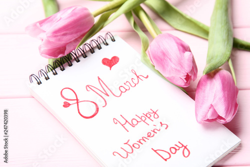Text 8 March Happy Women's Day with pink tulip flowers on wooden table