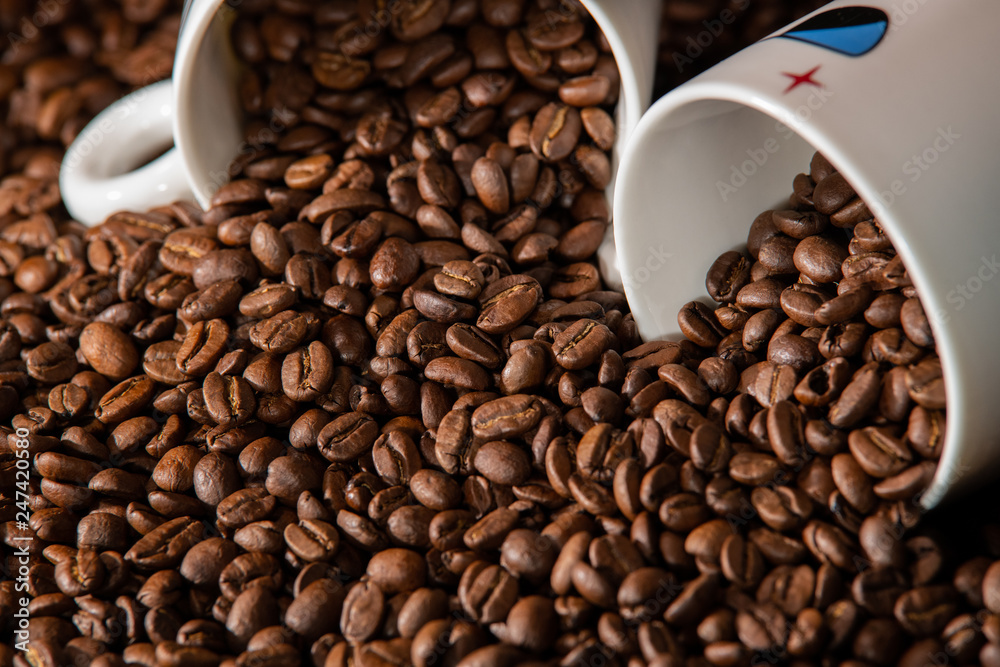 white cups with a pattern and grains of coffee on a black background