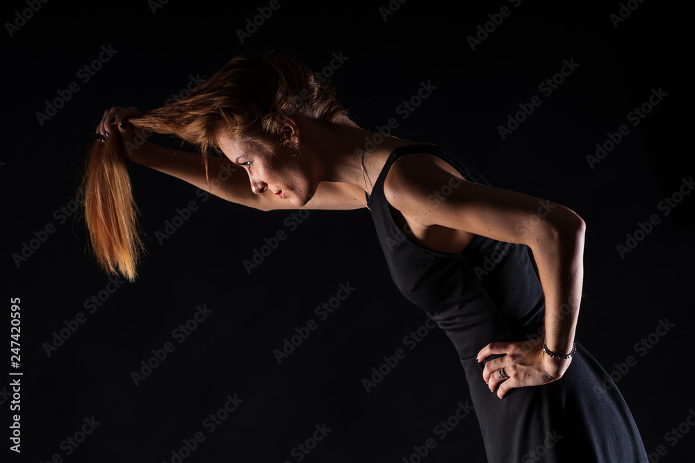 Caucasian white female model portrait. The wind blowing the long blonde hair off on beautiful girl. Woman posing studio shot on a black background Caucasian white female model portrait. The wind blowing the long blonde hair off on beautiful girl. Woman posing studio shot on a black background